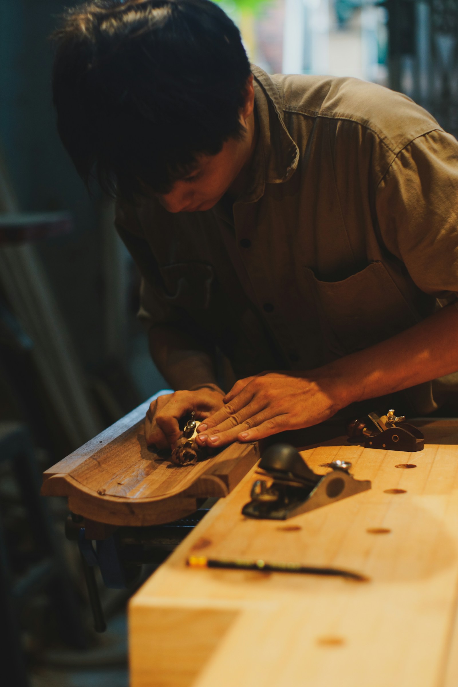 Asian craftsman shaping wood with focused, careful handwork